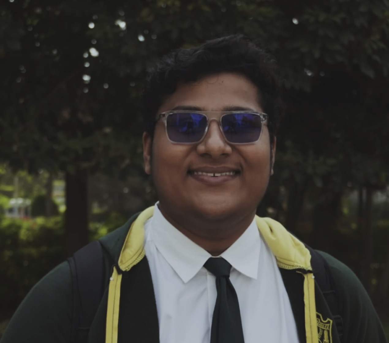 A student in sunglasses smiling in a school uniform